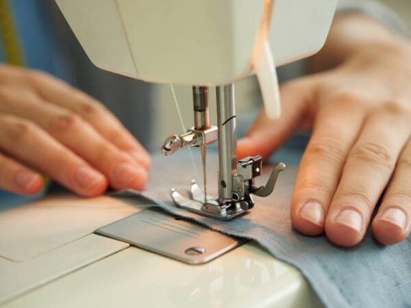 Hands of female tailor using sewing machine at work